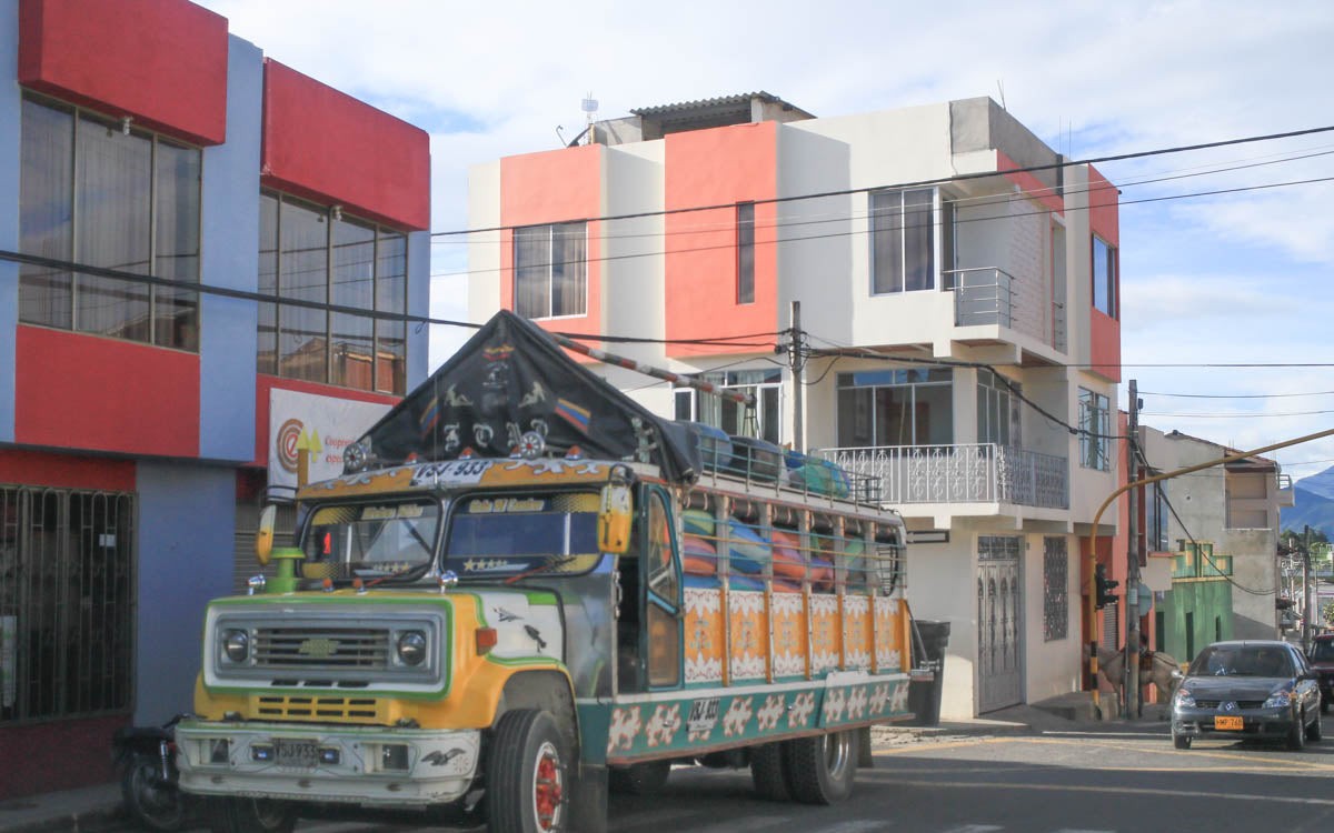 Colourful chiva bus carrying coffee bags through Buesaco town